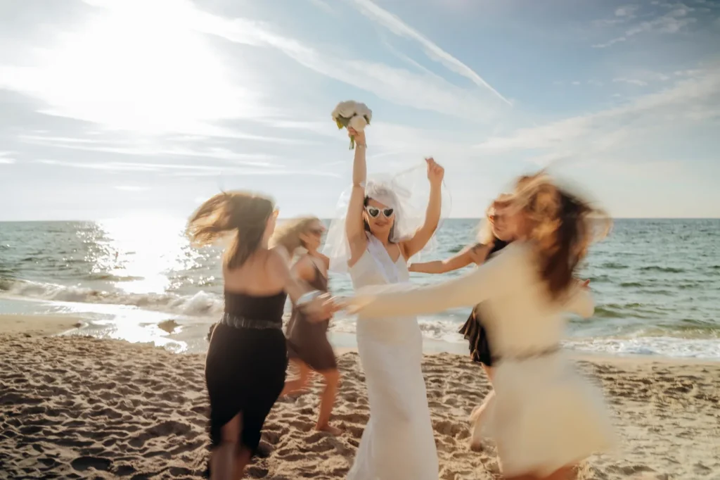 Panna młoda tańczy z przyjaciółkami na plaży, ruch rozmyty
